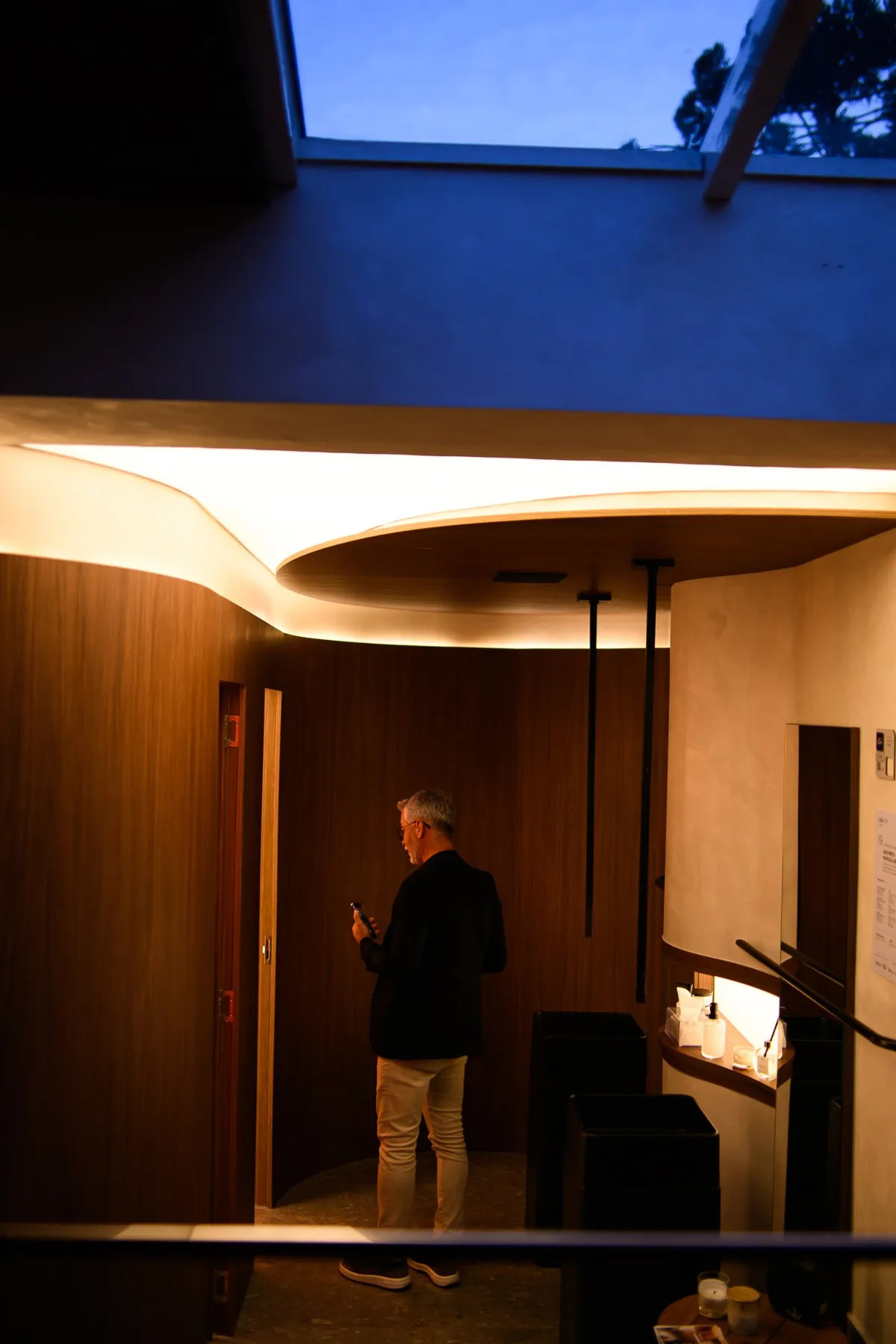 Hall executado com parede curva em madeira e forro iluminado