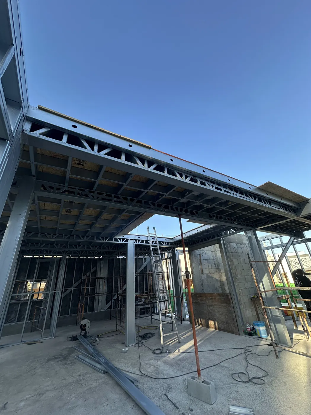 Estrutura metálica em Steel Framing vista de baixo, com a laje e o céu ao fundo